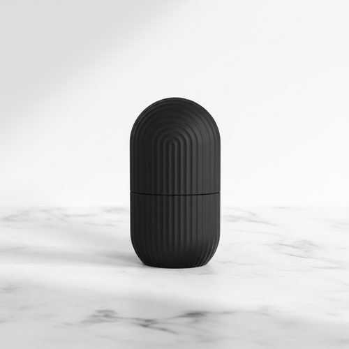 Black capsule ice roller on white marble surface